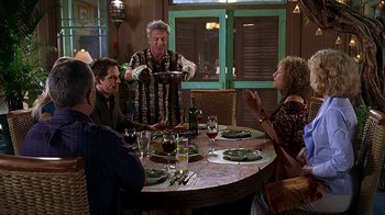 Movie still from “Meet the Fockers” (2004), directed by Jay Roach – A group of people sitting around a table with plates of food on it; Wide shot, Over the shoulder angle