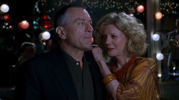 Movie still from “Meet the Fockers” (2004), directed by Jay Roach – An older man and a younger woman standing next to each other in front of lights; Close Up shot, Low angle