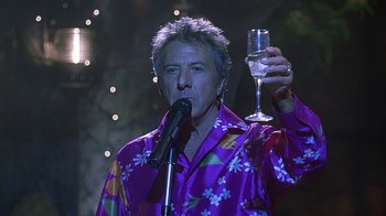 Movie still from “Meet the Fockers” (2004), directed by Jay Roach – A man holding a wine glass while standing on a stage; Medium shot, Low angle