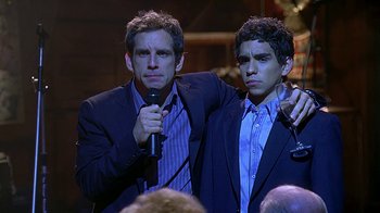 Movie still from “Meet the Fockers” (2004), directed by Jay Roach – Two men in suits are holding microphones; Medium shot, Over the shoulder angle