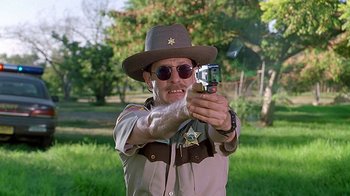 Movie still from “Meet the Fockers” (2004), directed by Jay Roach – A man in a sheriff's outfit holding a gun; Medium shot, Low angle