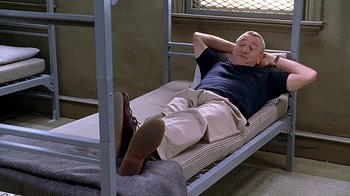 Movie still from “Meet the Fockers” (2004), directed by Jay Roach – An older man laying on top of a metal bed frame; Medium shot, High angle