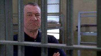 Movie still from “Meet the Fockers” (2004), directed by Jay Roach – An older man standing behind bars in a jail cell; Close Up shot, Over the shoulder angle