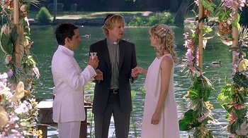 Movie still from “Meet the Fockers” (2004), directed by Jay Roach – A man and a woman exchanging wedding vows with a priest; Medium shot, Over the shoulder angle
