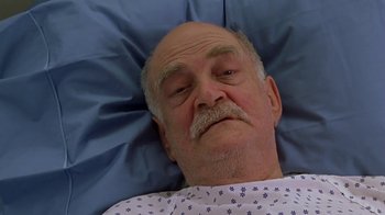 Movie still from “Meet the Parents” (2000), directed by Jay Roach – An older man laying in a hospital bed; Close Up shot, High angle