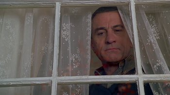 Movie still from “Meet the Parents” (2000), directed by Jay Roach – A man looking out of a window at the camera; Close Up shot, Low angle