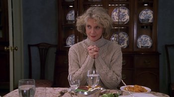 Movie still from “Meet the Parents” (2000), directed by Jay Roach – A woman sitting at a dinner table in front of plates of food; Medium shot, Over the shoulder angle