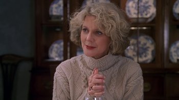Movie still from “Meet the Parents” (2000), directed by Jay Roach – An older woman wearing a sweater and holding a wine glass; Close Up shot, Over the shoulder angle