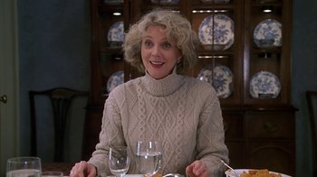 Movie still from “Meet the Parents” (2000), directed by Jay Roach – A woman sitting at a table with a glass of wine in front of her; Medium shot, Over the shoulder angle
