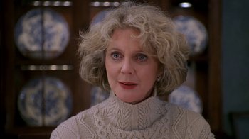 An older woman wearing a white sweater and looking at the camera