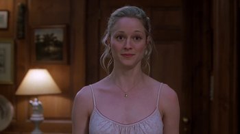 Movie still from “Meet the Parents” (2000), directed by Jay Roach – A woman in a white top is standing in a room; Medium shot, Over the shoulder angle