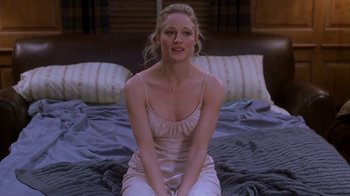 Movie still from “Meet the Parents” (2000), directed by Jay Roach – A woman sitting on top of a bed wearing a white dress; Medium shot, High angle