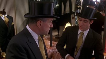 Movie still from “Meet the Parents” (2000), directed by Jay Roach – A man in a top hat and a woman in a suit and tie; Medium shot, Over the shoulder angle