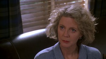 Movie still from “Meet the Parents” (2000), directed by Jay Roach – An older woman sitting on a couch looking at the camera; Close Up shot, Over the shoulder angle