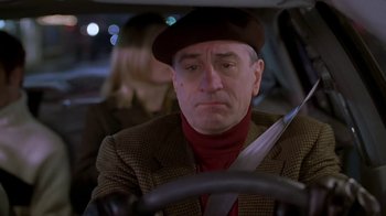 Movie still from “Meet the Parents” (2000), directed by Jay Roach – A man driving a car while holding a knife in his hand; Close Up shot, Over the shoulder angle