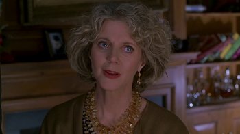 Movie still from “Meet the Parents” (2000), directed by Jay Roach – An older woman wearing a gold necklace and a brown jacket; Close Up shot, Over the shoulder angle