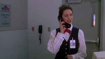 Movie still from “Meet the Parents” (2000), directed by Jay Roach – A woman talking on a phone while wearing a tie; Medium shot, Over the shoulder angle