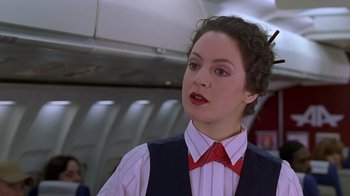 Movie still from “Meet the Parents” (2000), directed by Jay Roach – A woman in a red bow tie standing on an airplane; Close Up shot, Low angle