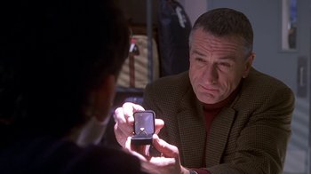 Movie still from “Meet the Parents” (2000), directed by Jay Roach – A man holding up a ring in his hand while looking at it; Close Up shot, Over the shoulder angle
