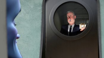 Movie still from “Megamind” (2010), directed by Tom McGrath – A man in a suit and tie looking out a round window; Medium shot, Over the shoulder angle