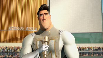 Movie still from “Megamind” (2010), directed by Tom McGrath – A man with a microphone standing in front of a building; Medium shot, Low angle