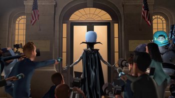 Movie still from “Megamind” (2010), directed by Tom McGrath – An image of an animated character being interviewed by the press; Medium shot, Over the shoulder angle