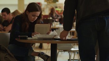 Movie still from “Men, Women & Children” (2014), directed by Jason Reitman – A girl sitting at a table reading a book; Medium shot, Over the shoulder angle
