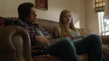 Movie still from “Men, Women & Children” (2014), directed by Jason Reitman – A man and a woman sitting on a couch with a guitar; Medium shot, Low angle