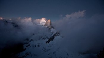 A view of a mountain peak in the clouds at night