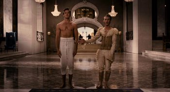 Movie still from “Mirror Mirror” (2012), directed by Tarsem Singh – Two men standing next to each other in a room with chandeliers; Wide shot, Low angle