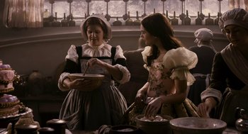 Movie still from “Mirror Mirror” (2012), directed by Tarsem Singh – Two women dressed in period clothing preparing a meal; Medium shot, High angle