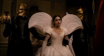 Movie still from “Mirror Mirror” (2012), directed by Tarsem Singh – A woman in a white dress with wings on her shoulders; Medium shot, Low angle