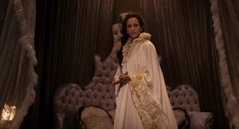 Movie still from “Mirror Mirror” (2012), directed by Tarsem Singh – A woman dressed in white holding a wand in a room; Medium shot, Low angle