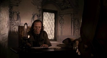 Movie still from “Mirror Mirror” (2012), directed by Tarsem Singh – A man sitting at a table reading a book; Medium shot, Over the shoulder angle