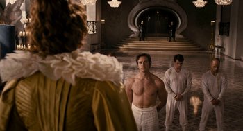 Movie still from “Mirror Mirror” (2012), directed by Tarsem Singh – A man with no shirt standing in front of two other men; Medium shot, Over the shoulder angle