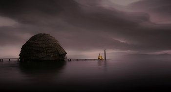 Movie still from “Mirror Mirror” (2012), directed by Tarsem Singh – A man sitting on a pier next to a hut; Extreme Wide shot, Low angle