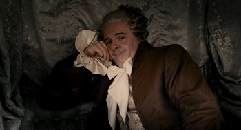 Movie still from “Mirror Mirror” (2012), directed by Tarsem Singh – An older man in a brown suit and a white bow tie; Medium shot, High angle