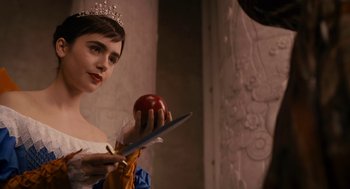 Movie still from “Mirror Mirror” (2012), directed by Tarsem Singh – A woman dressed as snow white holding an apple; Close Up shot, Over the shoulder angle