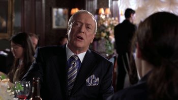 Movie still from “Miss Congeniality” (2000), directed by Donald Petrie – An older man wearing a suit and tie in front of other people; Medium shot, Over the shoulder angle
