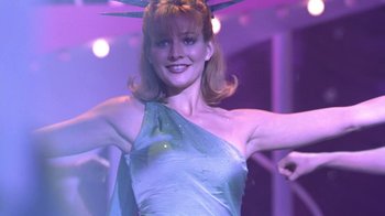 Movie still from “Miss Congeniality” (2000), directed by Donald Petrie – A woman in a blue dress is posing for the camera; Medium shot, Low angle