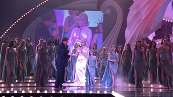 Movie still from “Miss Congeniality” (2000), directed by Donald Petrie – A group of people standing on a stage in front of an audience; Wide shot, Over the shoulder angle