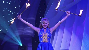 Movie still from “Miss Congeniality” (2000), directed by Donald Petrie – A woman in a blue dress holding two torches in her hands; Medium shot, Low angle