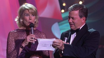 Movie still from “Miss Congeniality” (2000), directed by Donald Petrie – A man and a woman holding microphones in front of a microphone; Close Up shot, Over the shoulder angle