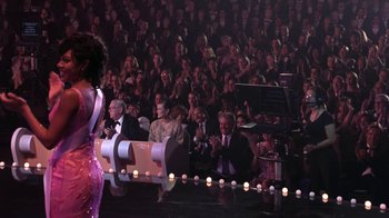 Movie still from “Miss Congeniality” (2000), directed by Donald Petrie – A crowd of people sitting and standing in front of a stage; Wide shot, Over the shoulder angle