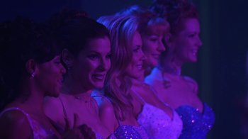 Movie still from “Miss Congeniality” (2000), directed by Donald Petrie – A group of women standing next to each other in front of purple lights; Medium shot, Low angle
