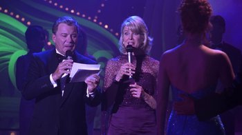 Movie still from “Miss Congeniality” (2000), directed by Donald Petrie – A man and a woman sing into microphones on a stage; Medium shot, Low angle