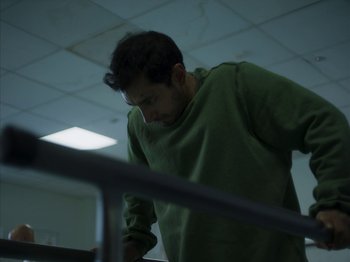 A man in a green shirt looking down at a table