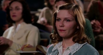 Movie still from “Mona Lisa Smile” (2003), directed by Mike Newell – A young woman is sitting in front of a group of people; Close Up shot, Over the shoulder angle