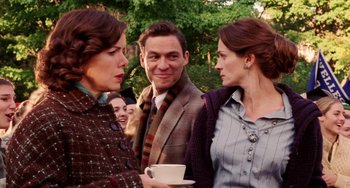 Movie still from “Mona Lisa Smile” (2003), directed by Mike Newell – A man and two women standing next to each other holding a cup; Medium shot, Over the shoulder angle