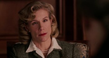 Movie still from “Mona Lisa Smile” (2003), directed by Mike Newell – A person sitting on a couch wearing a suit; Close Up shot, Over the shoulder angle